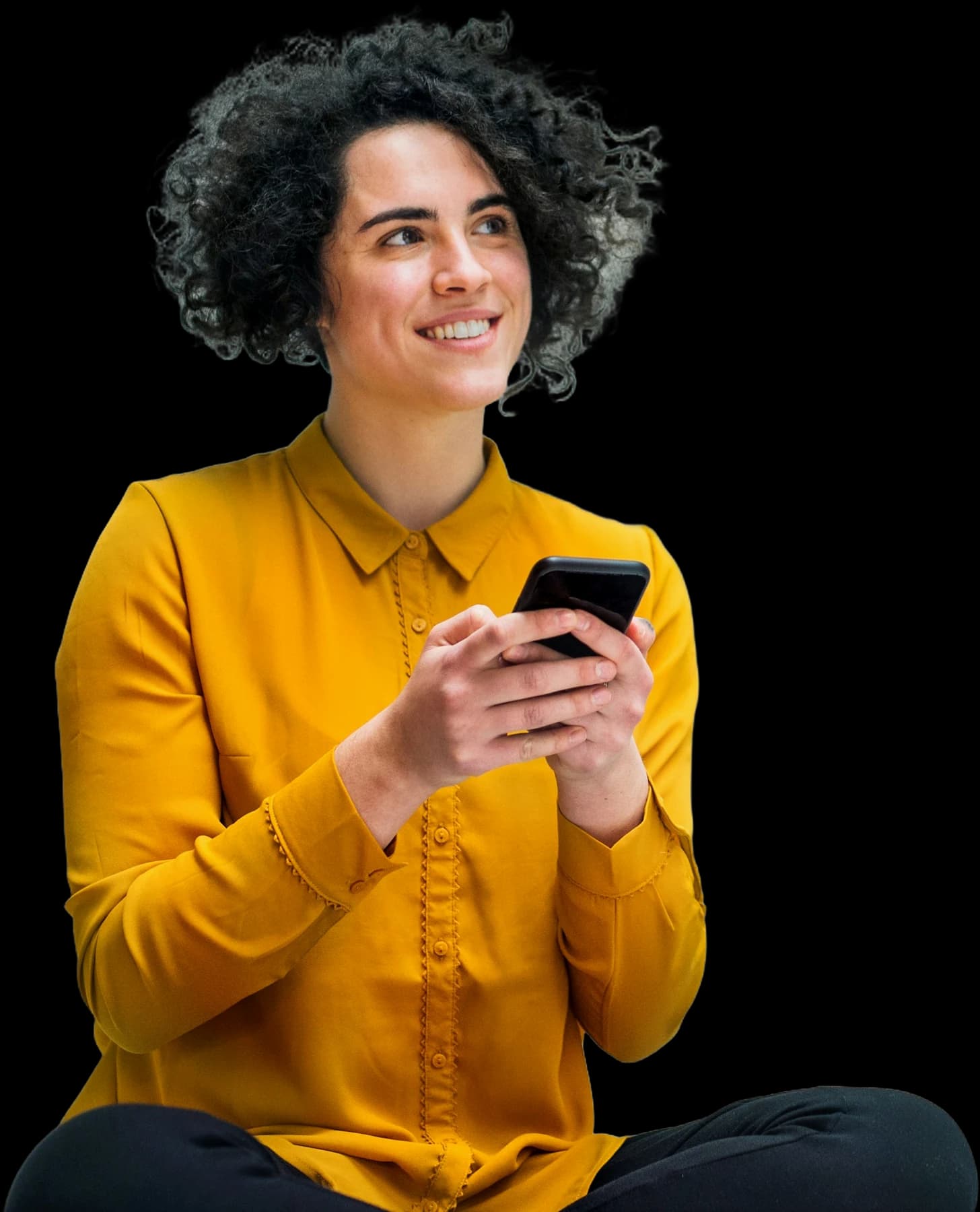 A woman sitting cross-legged, smiling as she checks her phone